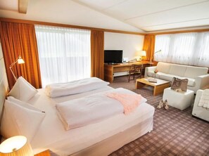 Une chambre d’hôtel comprenant un lit, un bureau, une télévision, un canapé et une table basse.