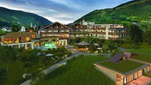 Un hotel moderno con varias construcciones, piscina y techo ajardinado.