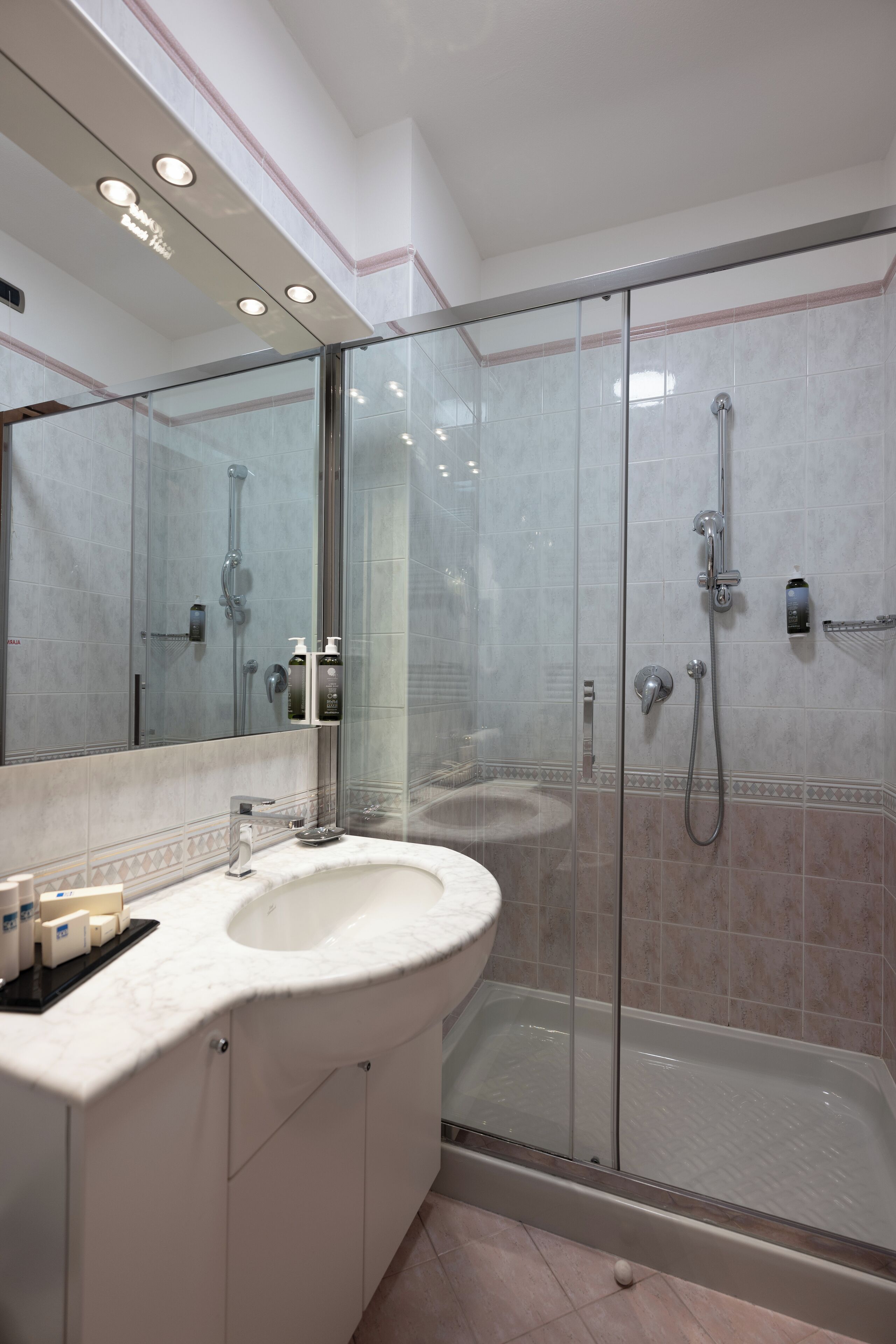 Un baño moderno con ducha de vidrio, un lavabo blanco y un espejo grande.