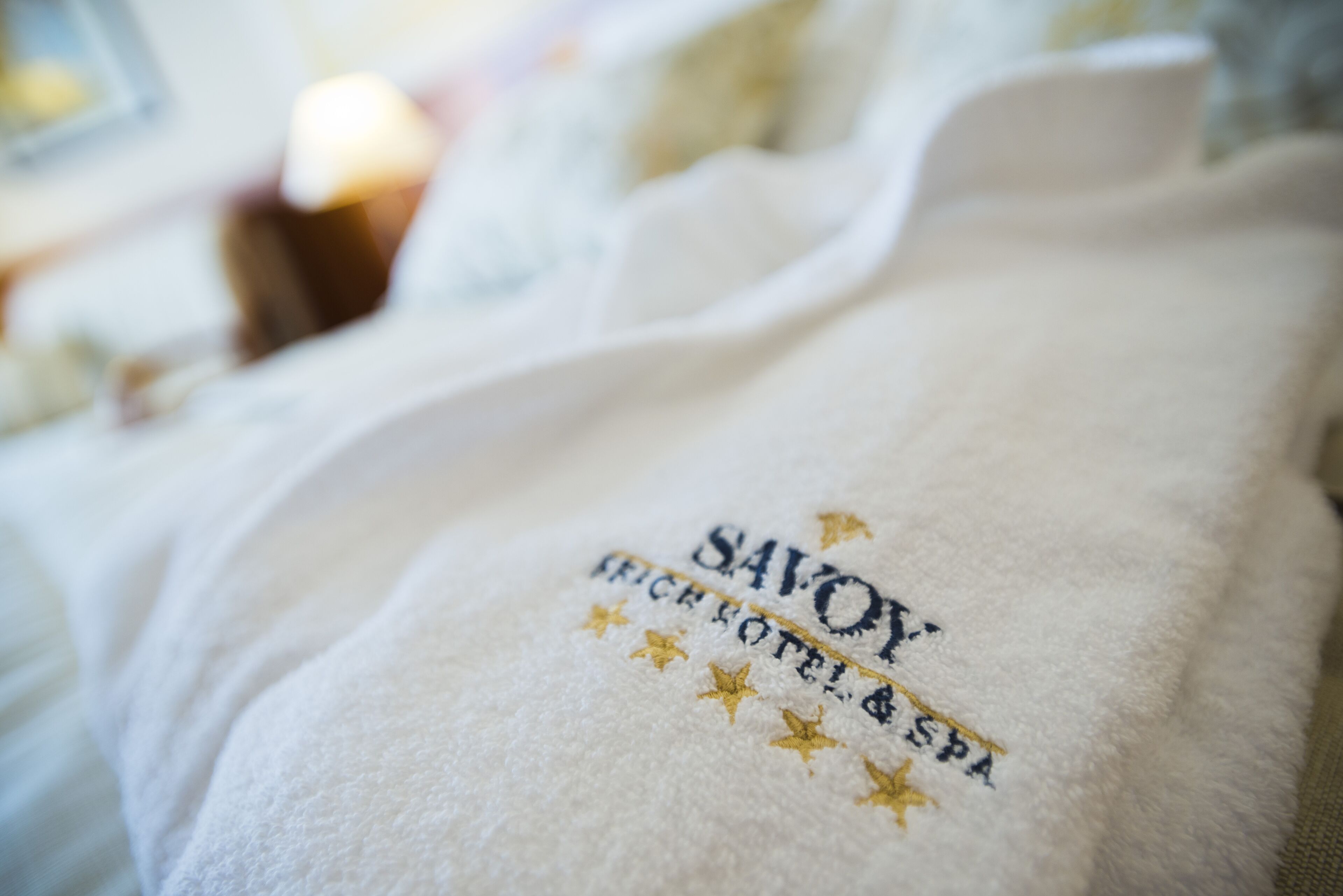 Une serviette blanche ornée d’une broderie portant l’inscription « SAVOY HOTEL & SPA ».