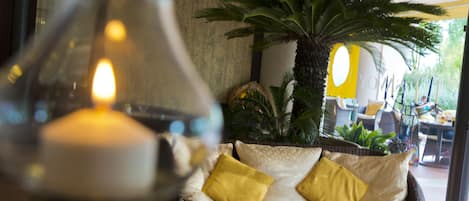 A cozy seating area with a wicker sofa, yellow cushions, and a potted palm plant.