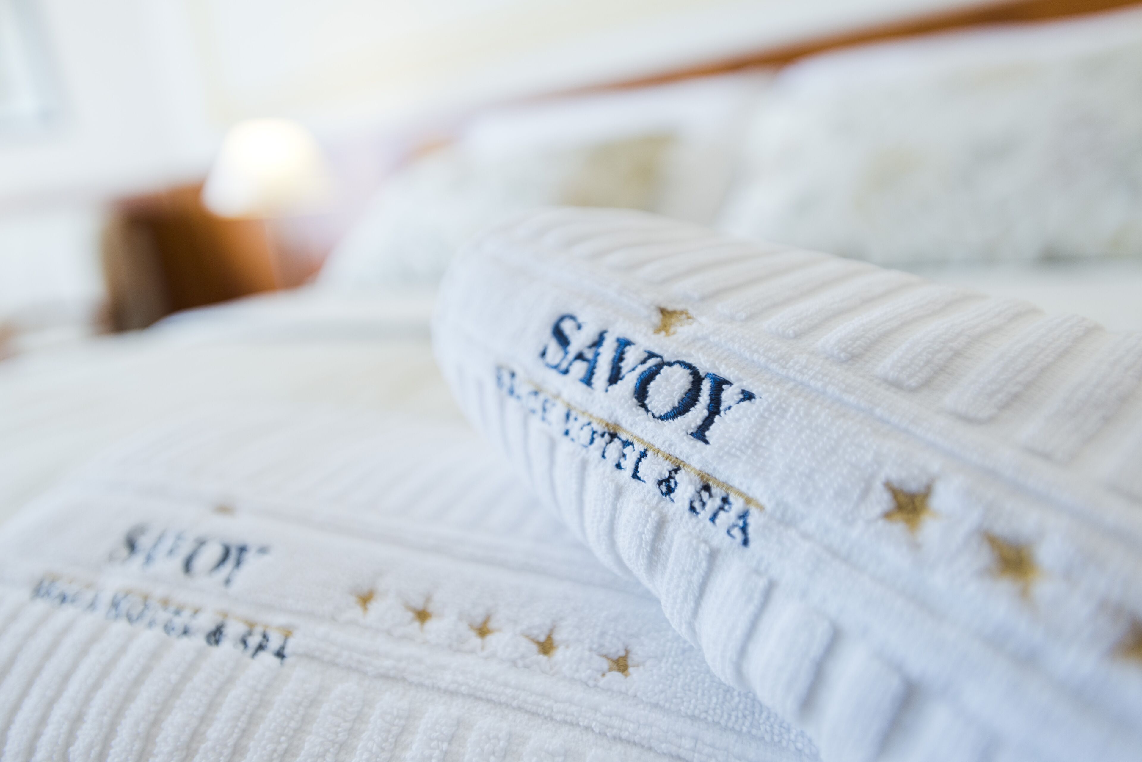 Primer plano de una toalla blanca con texto bordado y estrellas, probablemente de un hotel o spa.