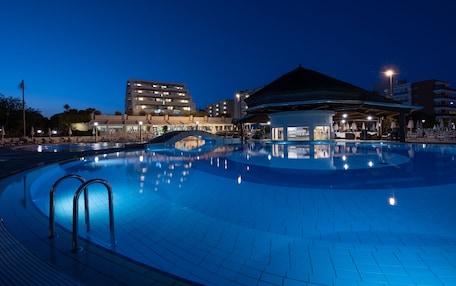 A swimming pool with a modern architectural setting, including a covered area and adjacent buildings.