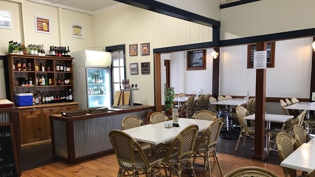 A restaurant with wicker chairs, a bar area with bottles, and a chalkboard menu. - Exchange Hotel Toogoolawah (Toogoolawah)