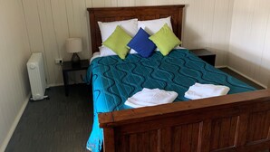 A neatly made bed with a blue patterned bedspread, white pillows, and a wooden headboard. - Exchange Hotel Toogoolawah (Toogoolawah)