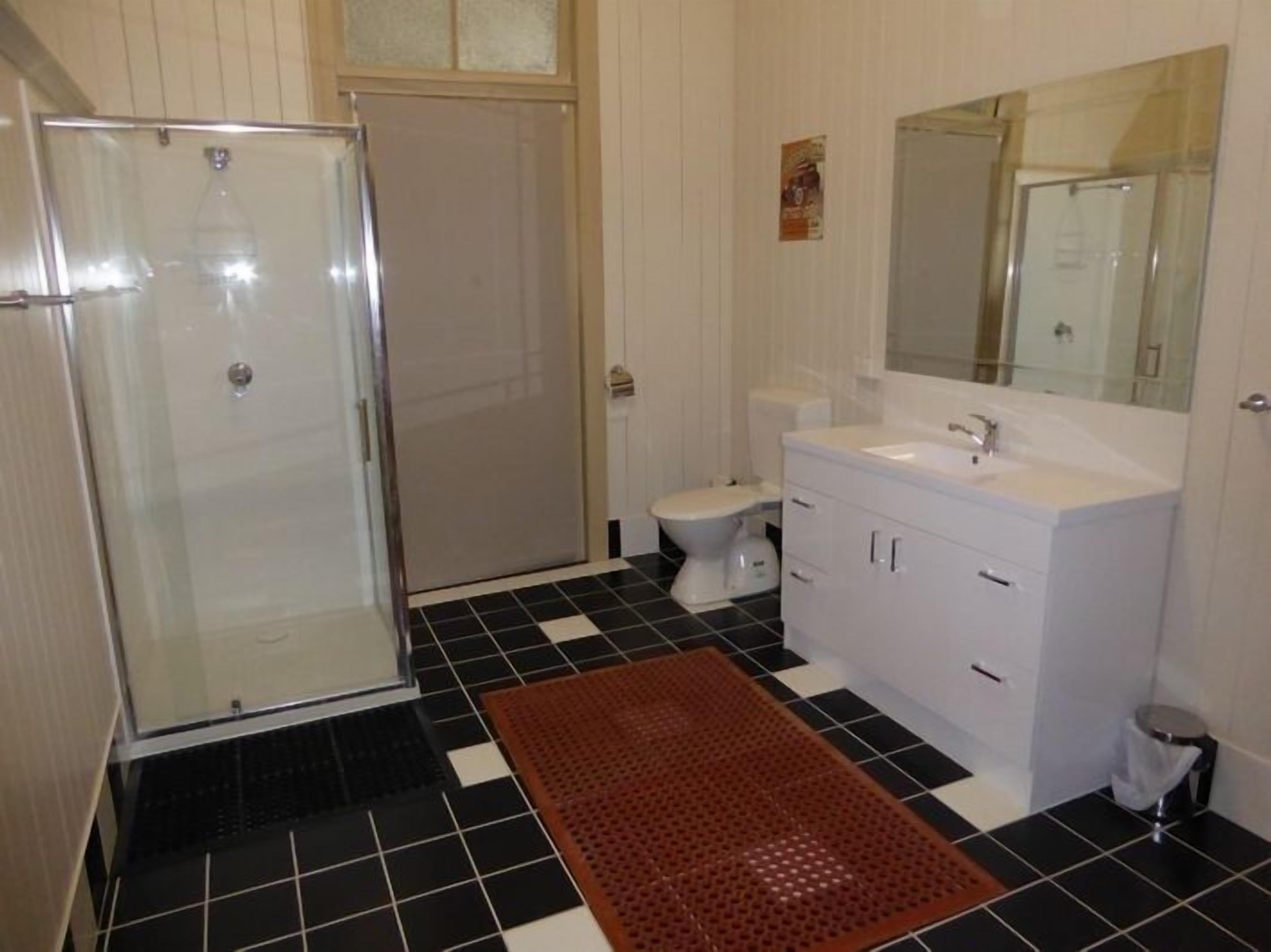 Un bagno con box doccia in vetro, un water, un lavandino con specchio e un pavimento piastrellato in bianco e nero.