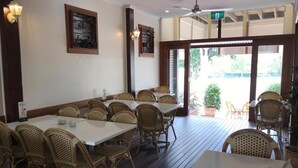 A restaurant with wooden tables and chairs, a ceiling fan, and a view of the outdoors. - Exchange Hotel Toogoolawah (Toogoolawah)