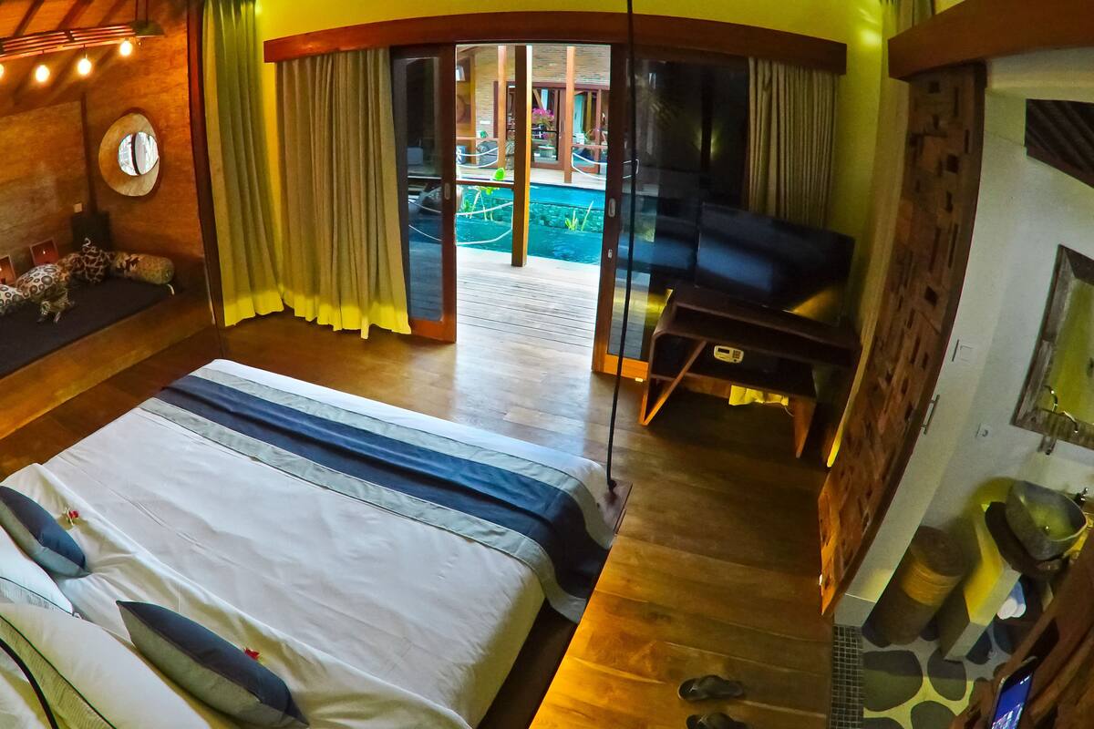 Een kamer met een bed, een slaapbank, een televisie en uitzicht op een zwembad.