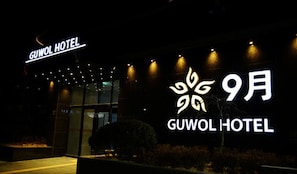 Exterior del HOTEL GUWOL con señalización iluminada y una fachada moderna.