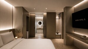 Une chambre d’hôtel moderne équipée d’un lit, d’une table de chevet, d’une télévision et donnant sur la salle de bain.