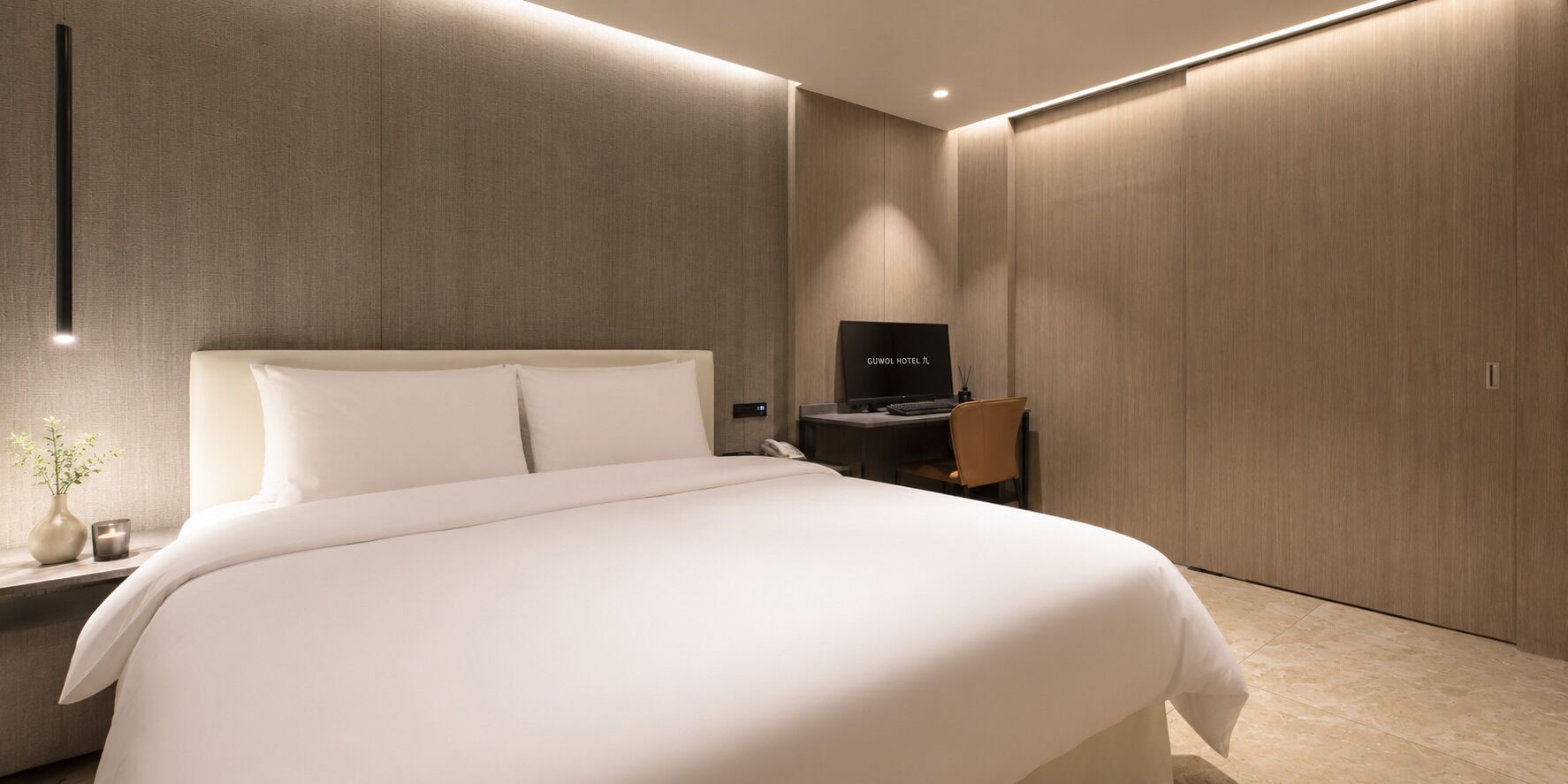 Una habitación de hotel moderna con una cama grande, televisión, escritorio y armario.