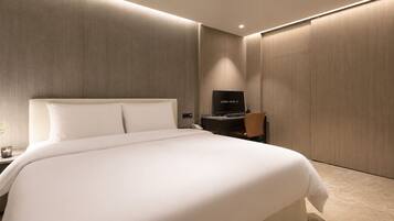 Una habitación de hotel moderna con una cama grande, televisión, escritorio y armario.