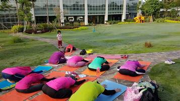 A group of people doing yoga on mats in an outdoor area with a building in the background.