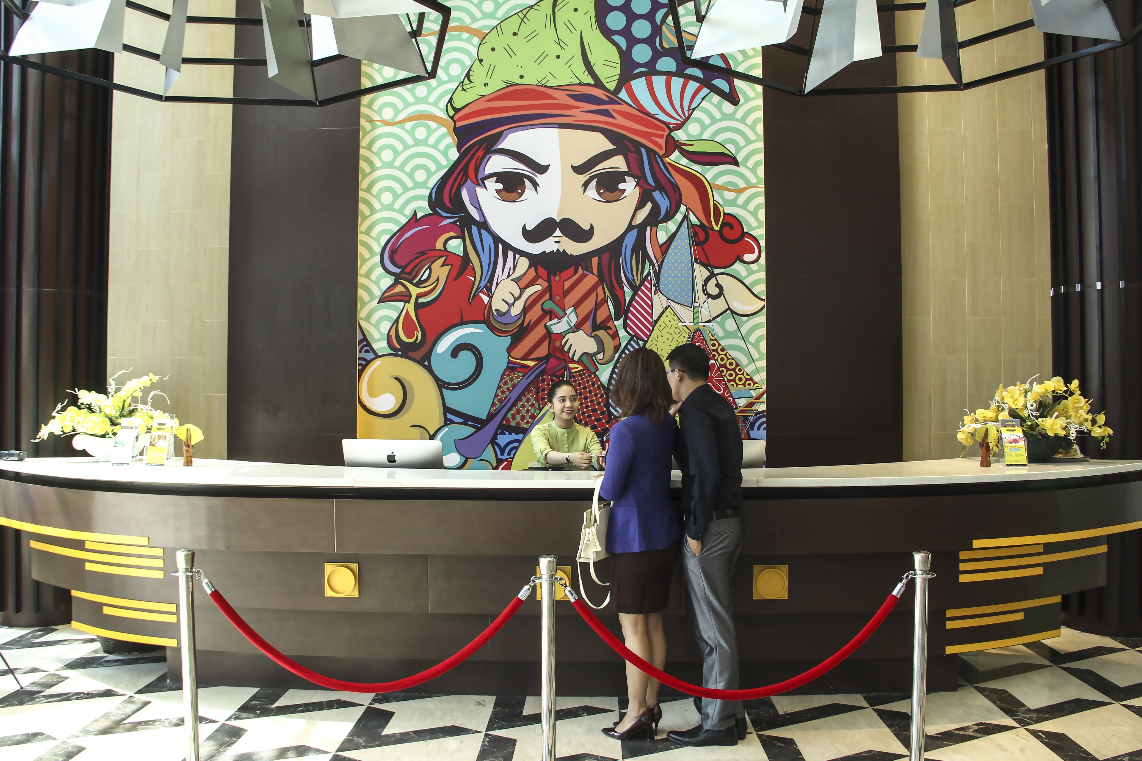 Una reception con un murale colorato, un banco di registrazione e una cordonata rossa.