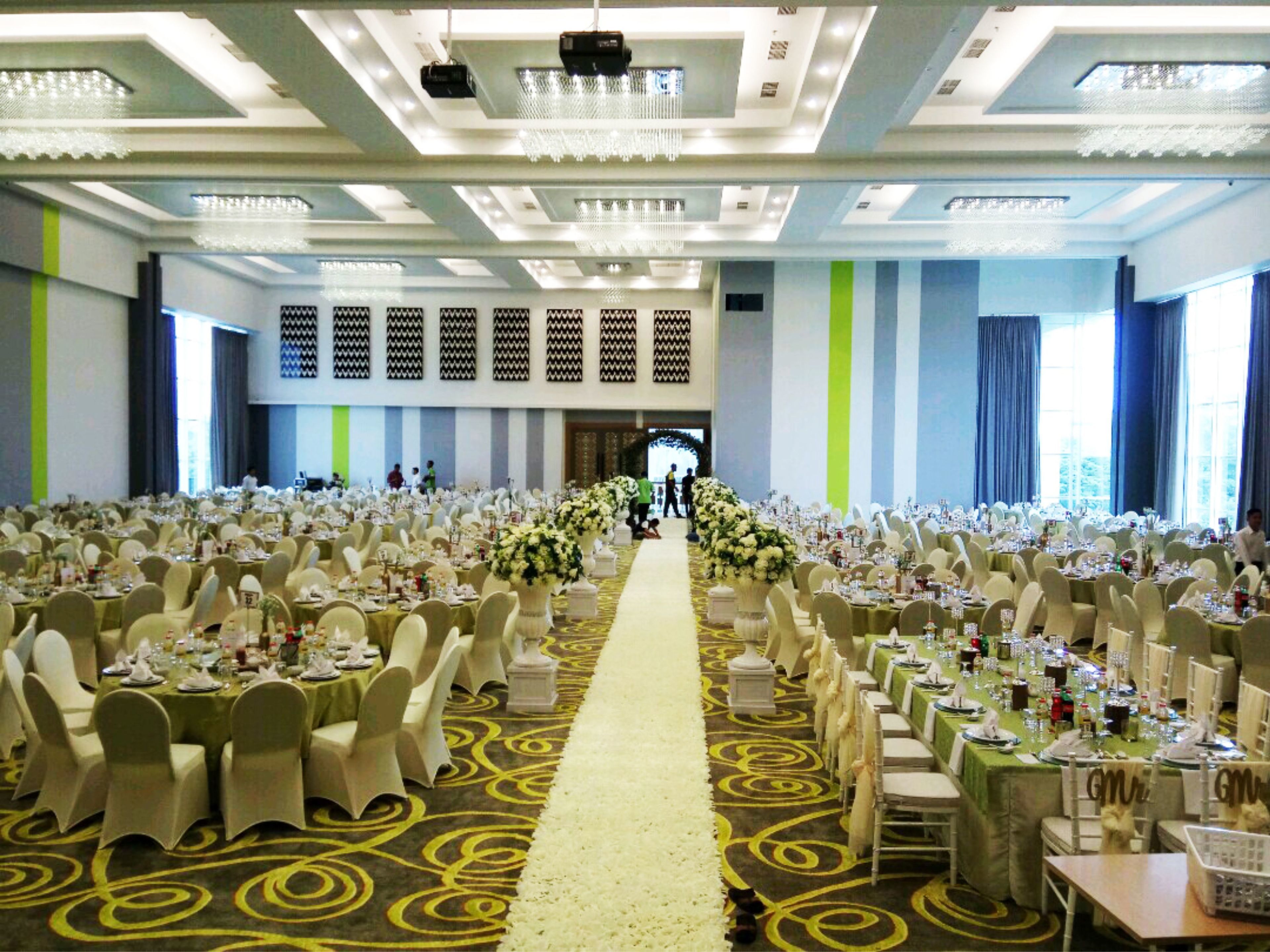 Une salle de banquet avec des rangées de tables, des chaises et une allée centrale.