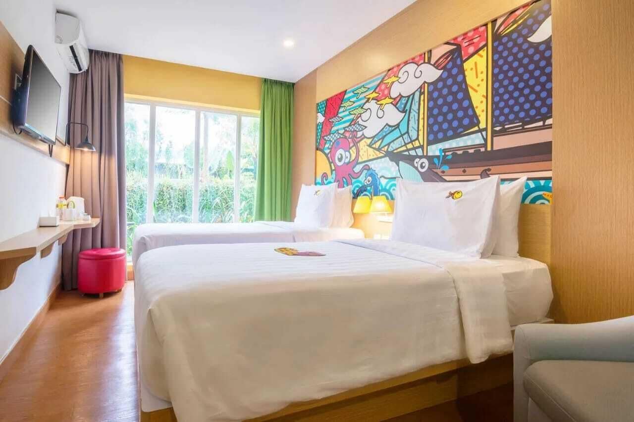 A hotel room with two beds, a TV, a painting, and a window with curtains.
