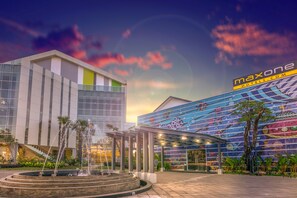 A modern hotel with a glass facade, a colorful mural, and a fountain in the courtyard. - MaxOneHotels.com Resort Makassar (Makassar)