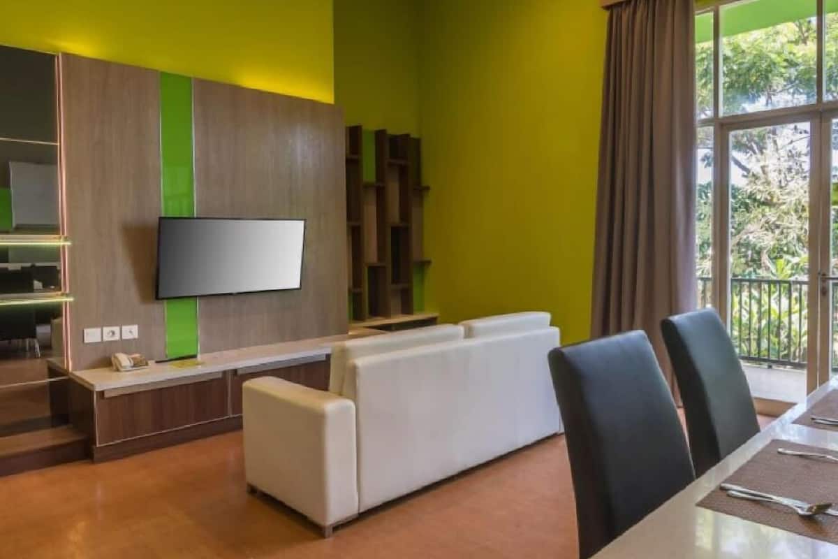Ein modernes Wohnzimmer mit Flachbildfernseher, einem weißen Sofa und einem Essbereich mit Tisch und Stühlen.