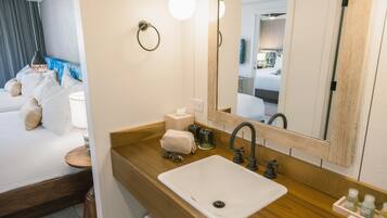 A modern bathroom with a wooden vanity, a white sink, a mirror, and a towel rack.