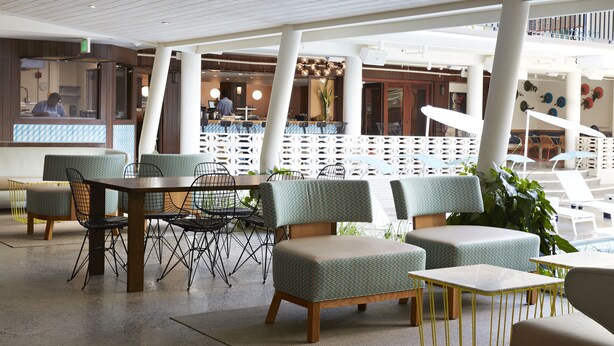 A spacious indoor area with seating arrangements, a counter, and a staircase. - The Surfjack Hotel & Swim Club (Honolulu)