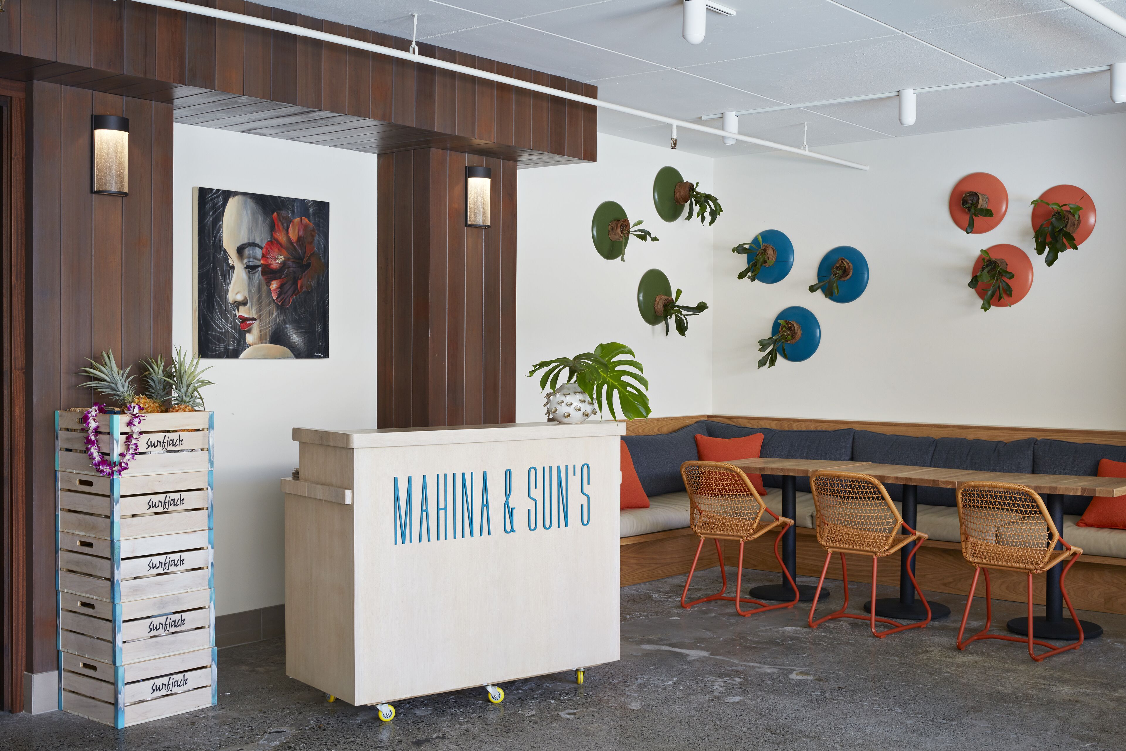 A reception area with a wooden reception desk, a wall-mounted plant display, and a seating area with wicker chairs and a sofa.