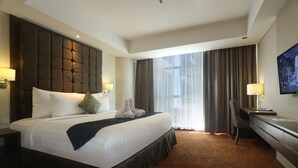Una camera d'albergo con un letto grande, una scrivania, una sedia e una TV appesa al muro.