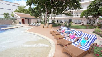 Relax by the resort pool, surrounded by lush greenery and comfortable lounge chairs.