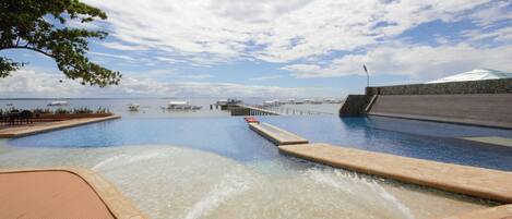 Una piscina con vistas al mar y un muro de piedra.