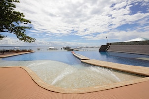 A swimming pool with a view of the sea and a stone wall.