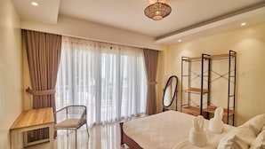 Une chambre d’hôtel avec un lit, un bureau, une chaise et une grande fenêtre avec des rideaux.