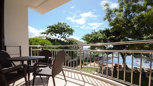 Un balcon avec une table et des chaises, donnant sur une piscine et un espace verdoyant.