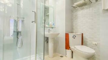 Un baño moderno con ducha de vidrio, lavamanos blanco y retrete.