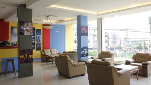 Um hall de hotel moderno com assentos confortáveis, janelas amplas e decoração colorida.