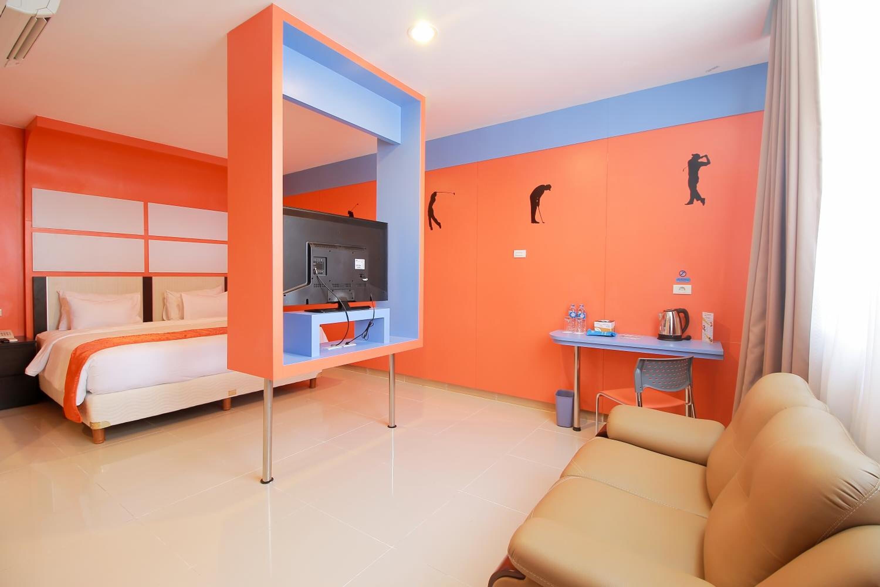 A hotel room with a bed, a TV, a desk, and a sofa.