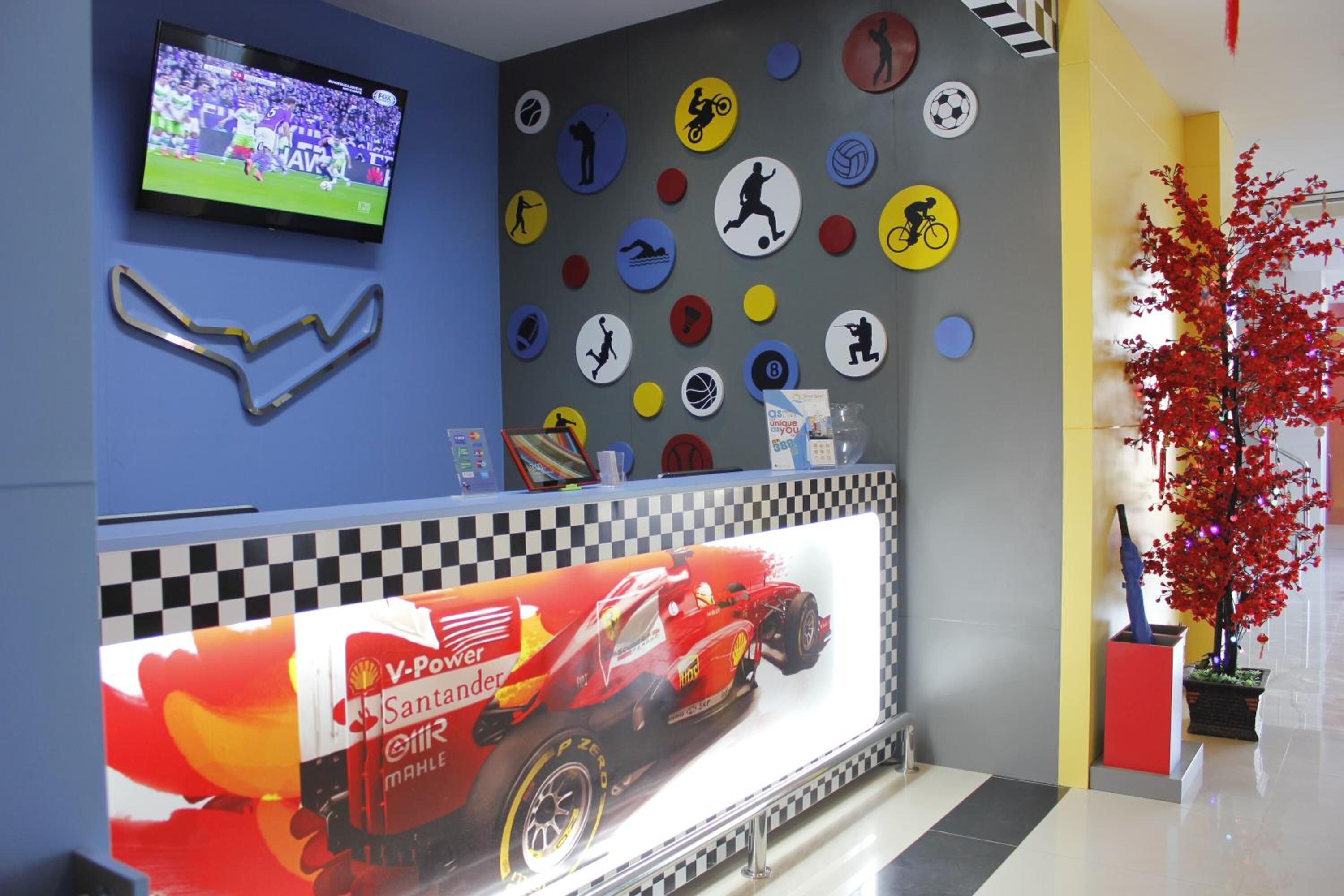 A reception area with a checkered floor, a large screen displaying a sports event, and a wall decorated with various sports icons.