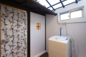 A room with a bamboo wallpaper, a toilet, a window with a view, and a skylight.