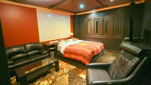 Una habitación de hotel con una cama, un sofá, una mesa de centro y un televisor.