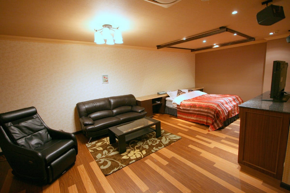 A room with a bed, a sofa, a chair, a small table, and a desk.