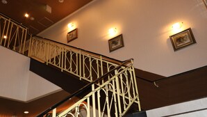 Una escalera con barandillas de metal ornamentadas y luces fijadas a la pared.