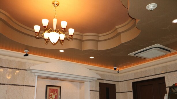 Zona de recepción de un hotel con candelabro, obras de arte enmarcadas, mostrador de recepción y una puerta.