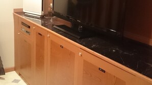 Eine Küche mit großem Flachbildfernseher an der Wand, einem weißen Kühlschrank und Holzschränken.