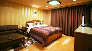 Ein Hotelzimmer mit Bett, Sofa, Schreibtisch und Fernseher.
