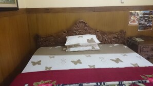 A bed with a wooden headboard, a white and red bedspread with butterfly patterns, and a red blanket at the foot of the bed. - Handika Hotel Mataram (Mataram)