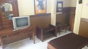A room with a wooden dresser, a television on a stand, a mirror, and a small table. - Handika Hotel Mataram (Mataram)