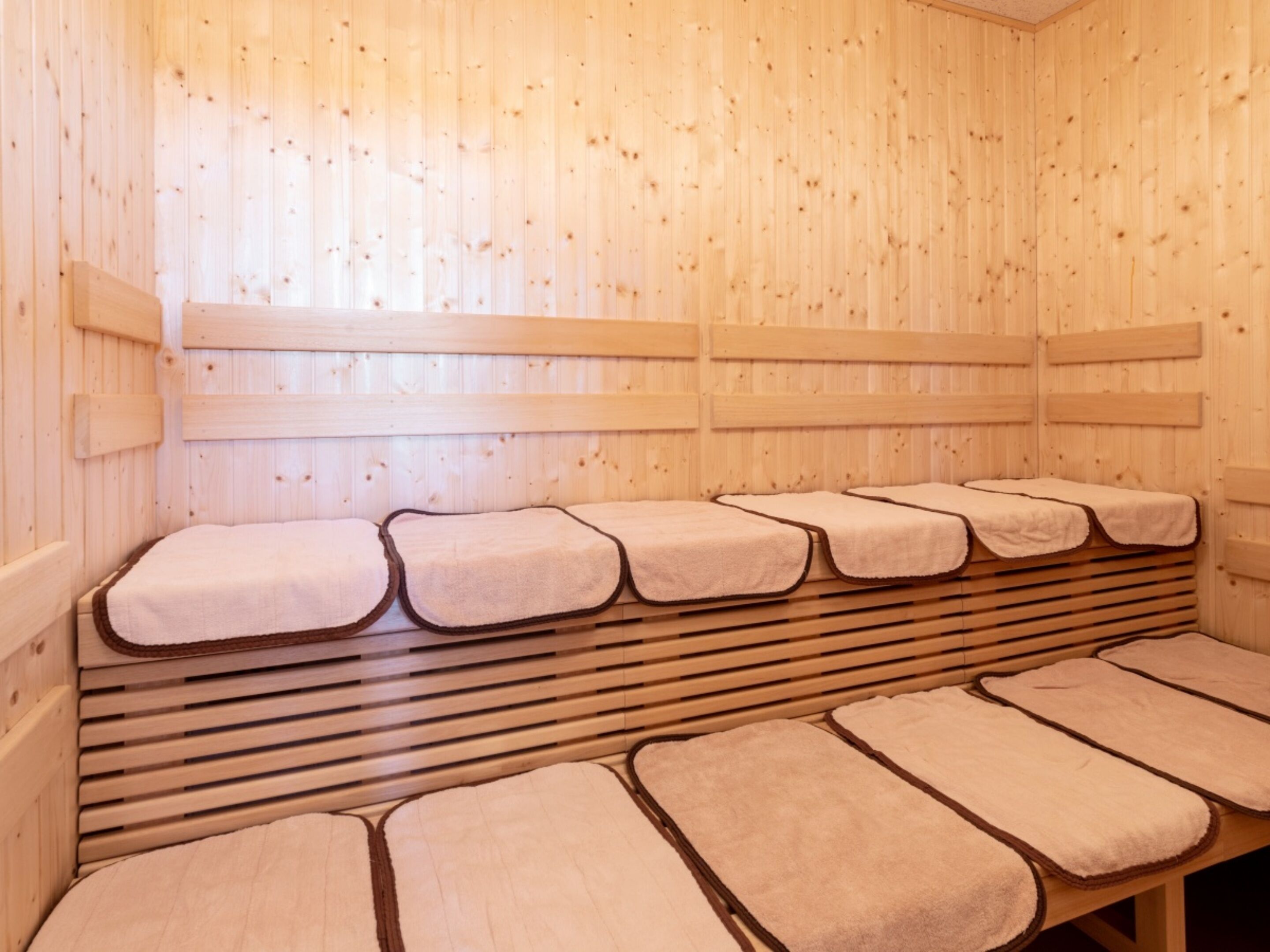 A sauna with wooden benches and benches covered with towels.
