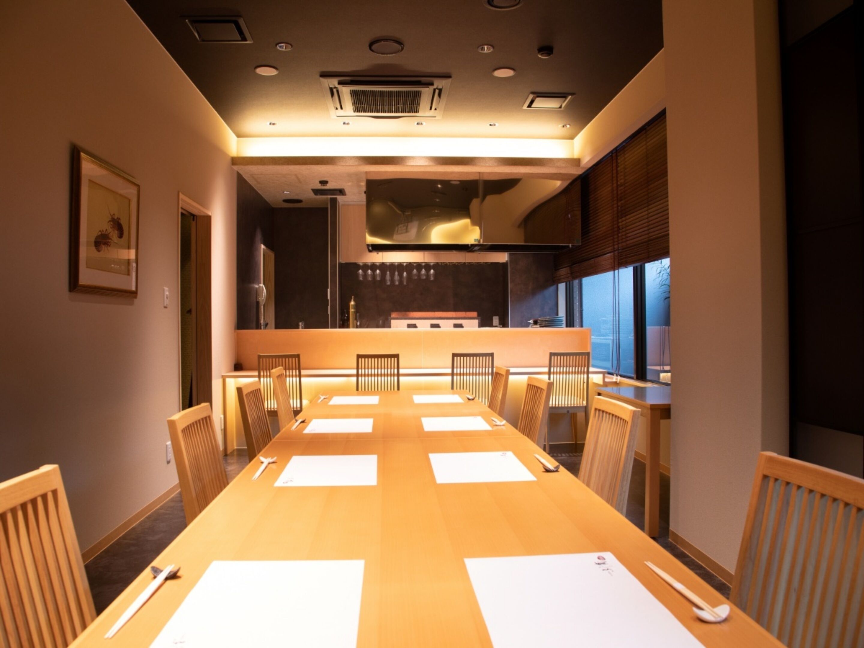 A conference room with a long table, chairs, and a kitchen area in the background.