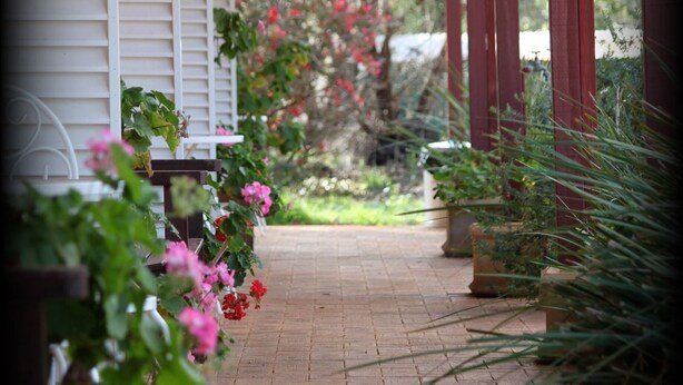 A covered porch with a brick pathway leading to a white building. - York Motel (York)