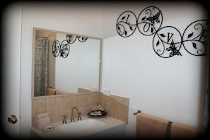 A bathroom with a large mirror, a sink, and decorative wall art. - York Motel (York)