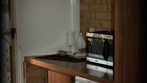 A compact kitchen with a wooden countertop, a white refrigerator, and a tiled backsplash. - York Motel (York)