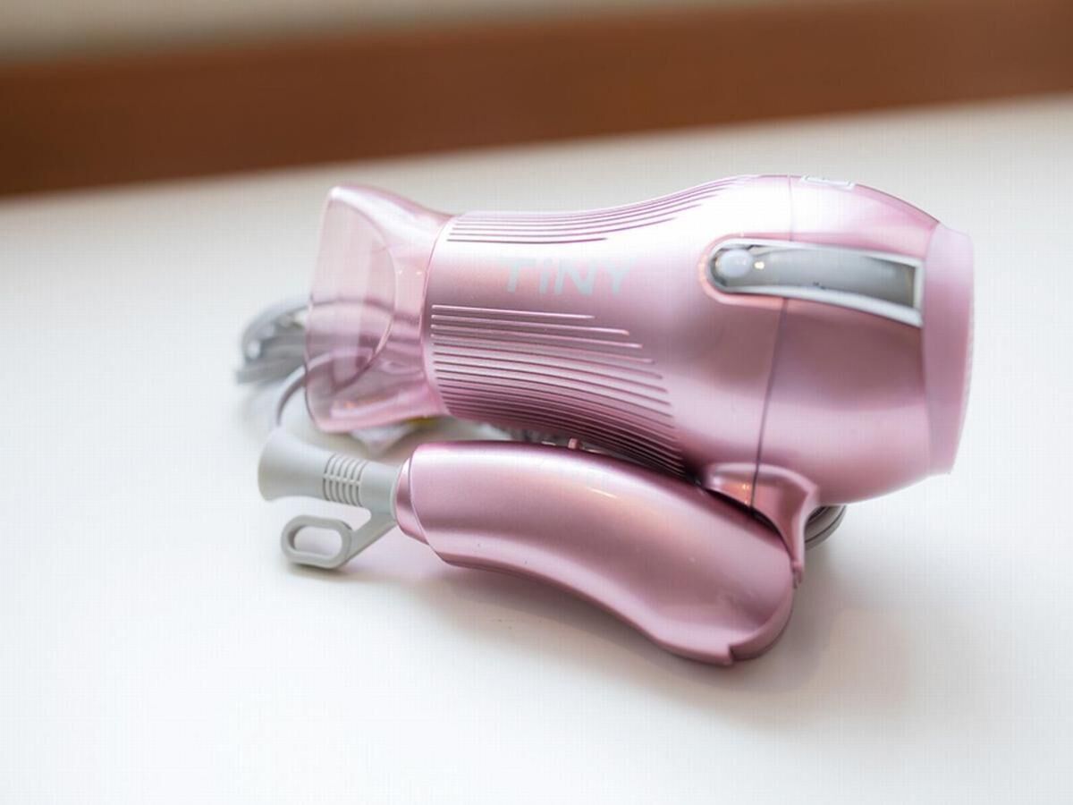 A pink hairdryer on a white surface.